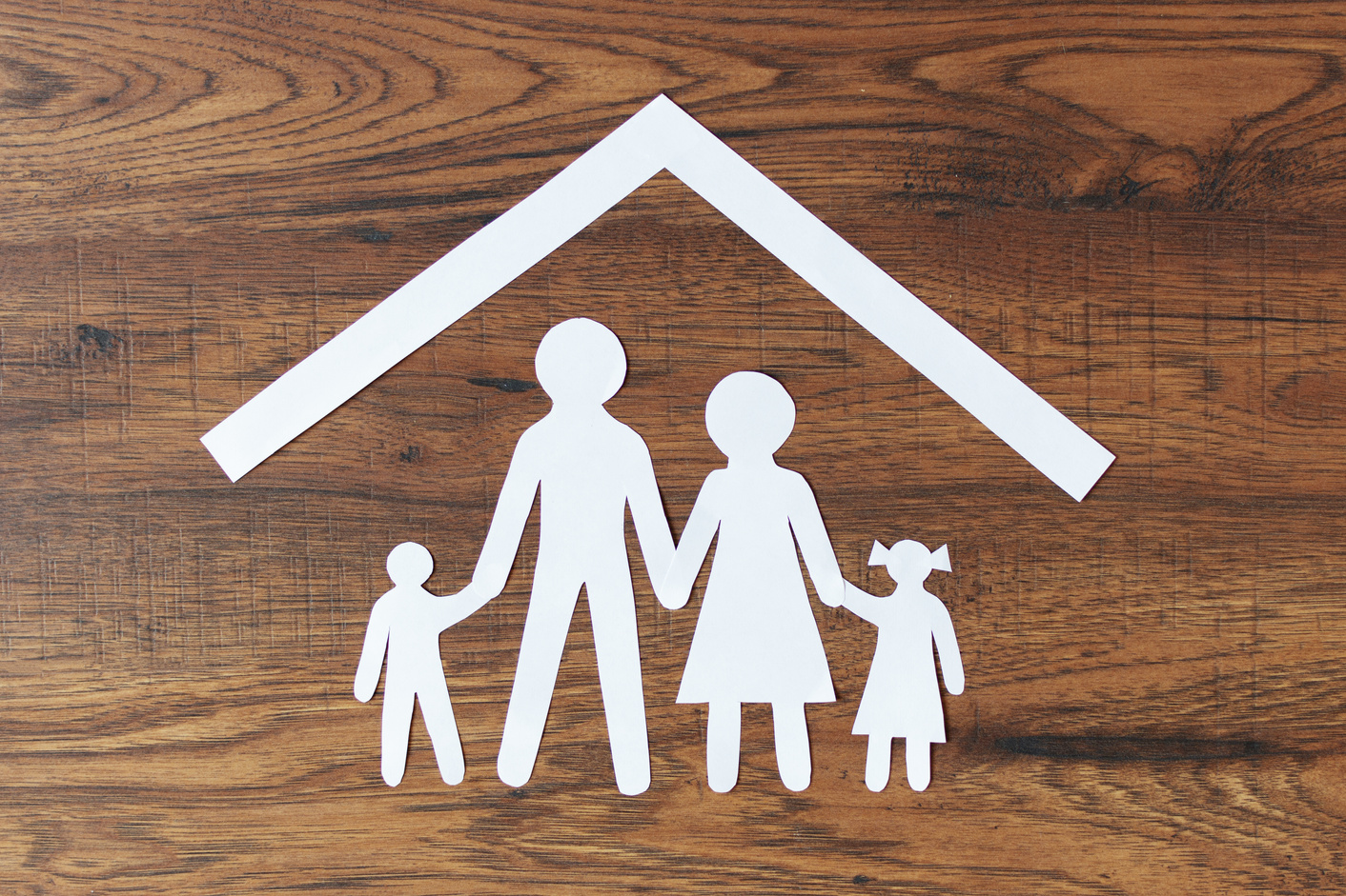 Paper Family Figure with Roof on Wooden Background